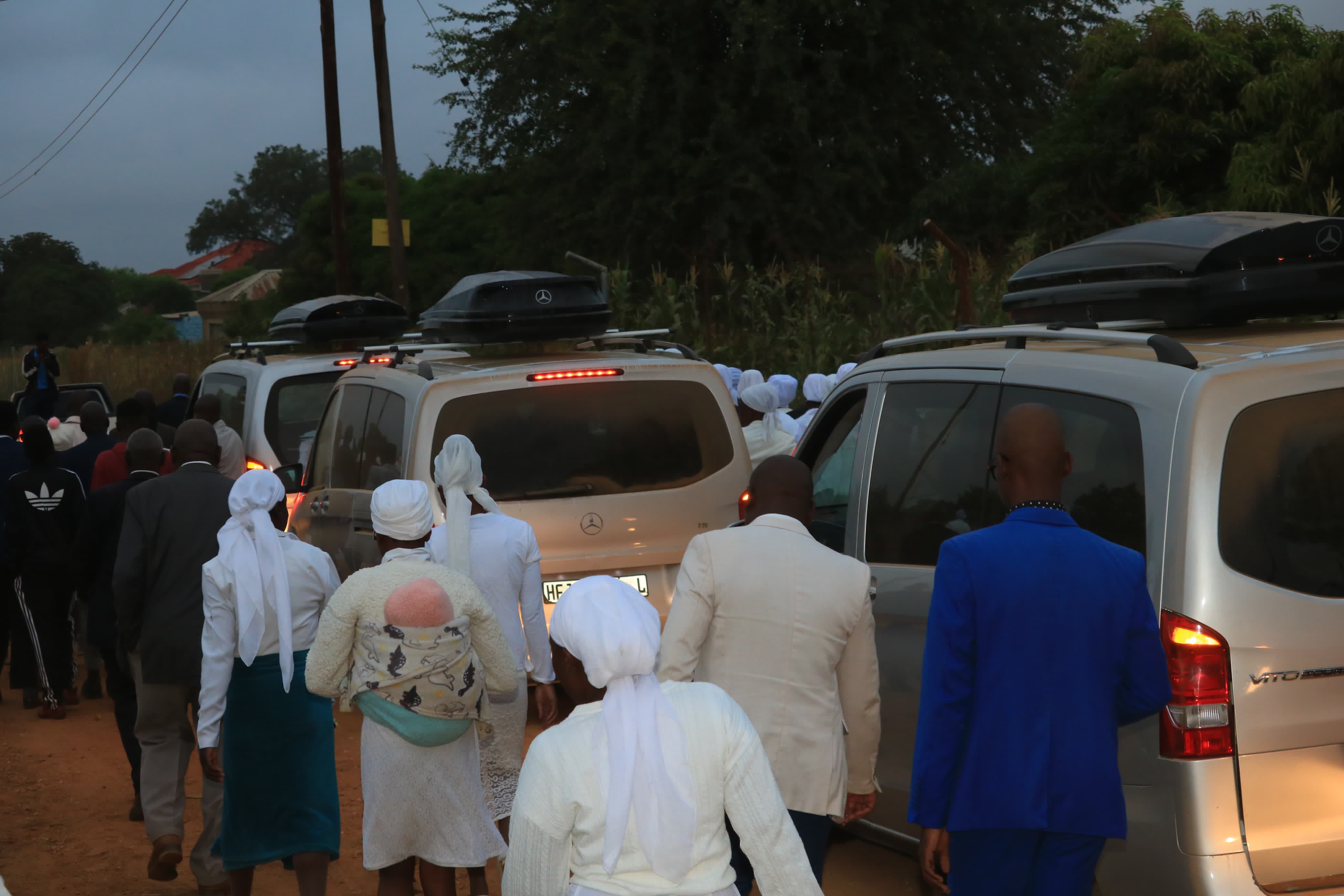 Funeral attendees walking alongside service vehicles